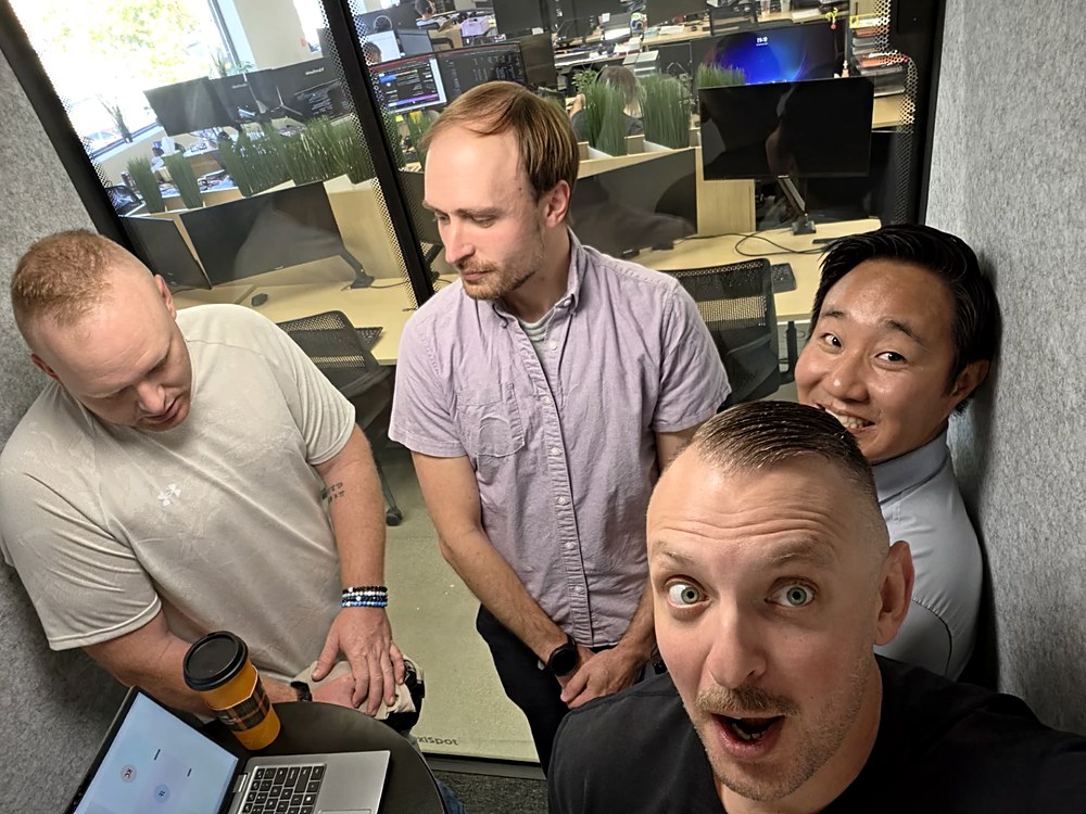 Team members gathered around a laptop